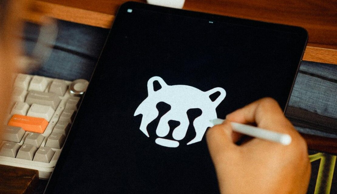 Main tenant un stylet qui dessine une tête d'animal stylisée sur une tablette graphique