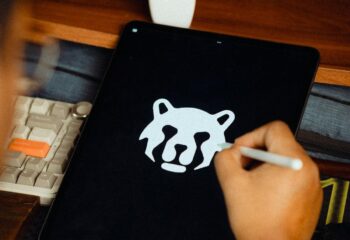 Main tenant un stylet qui dessine une tête d'animal stylisée sur une tablette graphique