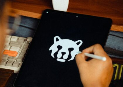 Main tenant un stylet qui dessine une tête d'animal stylisée sur une tablette graphique